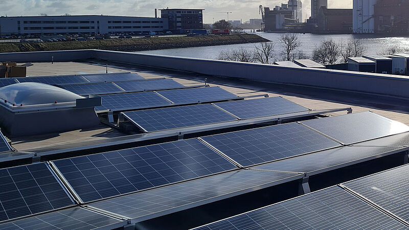 Photovoltaik-Anlage auf dem Flachdach eines hohem Hauses.