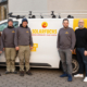 Auf dem Foto ist das Team von Solarfuchs, acht Personen, vor einem weißen Fahrzeug mit dem Logo "SOLARFUCHS" zu sehen. Das Fahrzeug trägt die Aufschrift "Erneuerbare Energien". Alle Personen sind in grauen Sweatshirts und beige Hosen gekleidet. Einige tragen auch Mützen oder Hüte. Sie stehen in einer Reihe, teilweise leicht nach links oder rechts gedreht.
